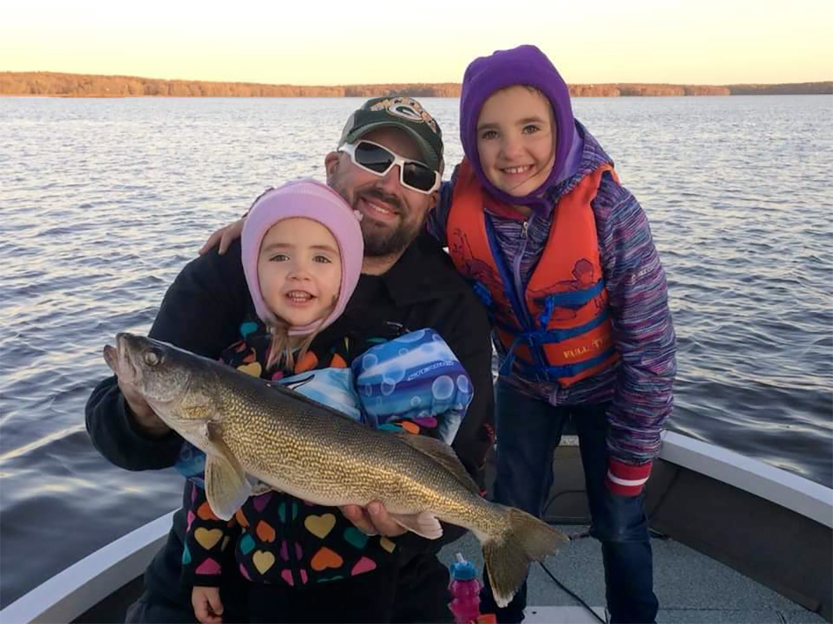 man holding walleye with his two children