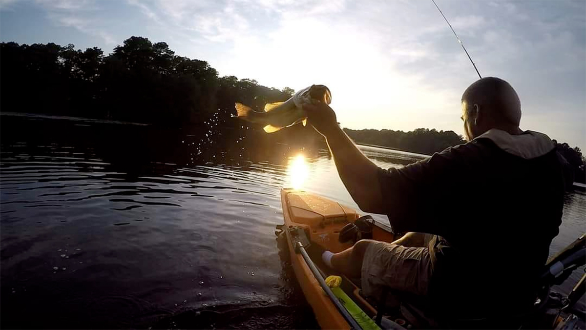 angler catching largemouth bass from kayak