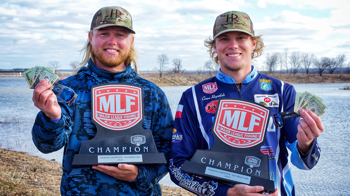 two college fishermen holding trophies while smiling