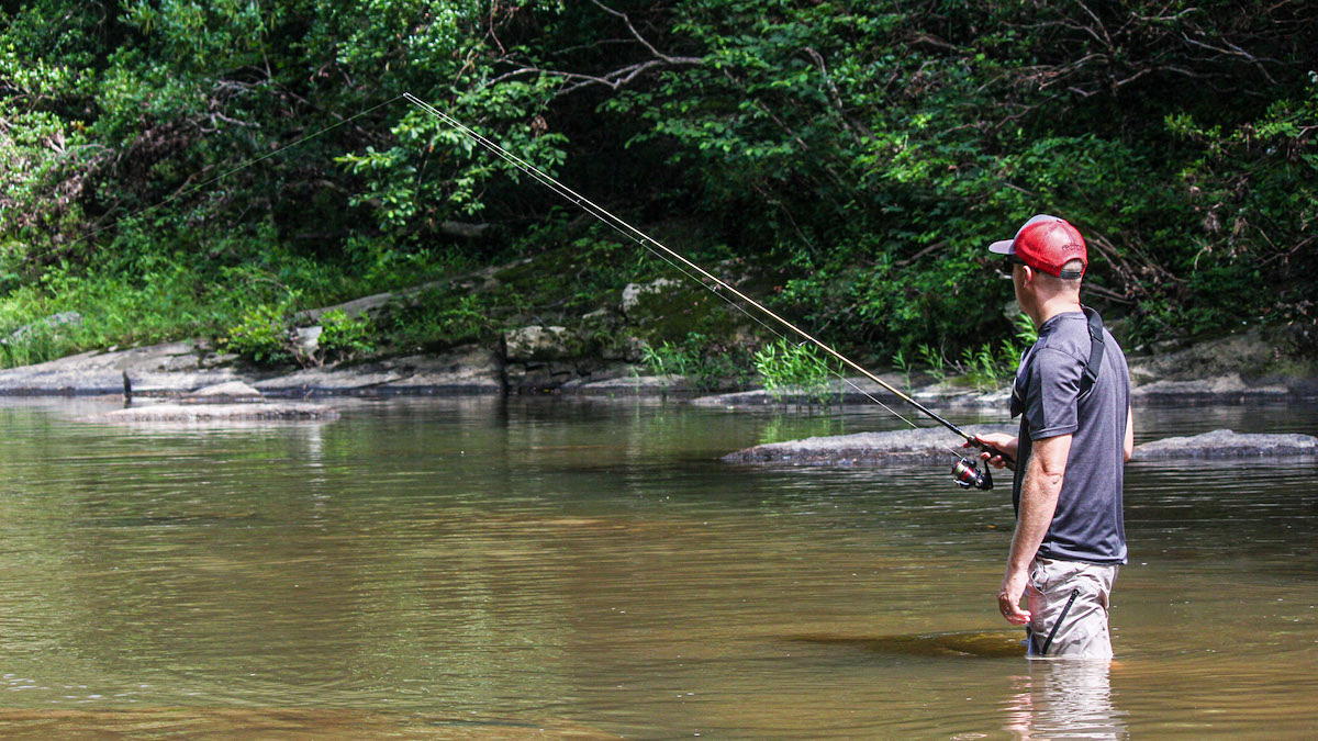 angler wade fishing in shallow creek