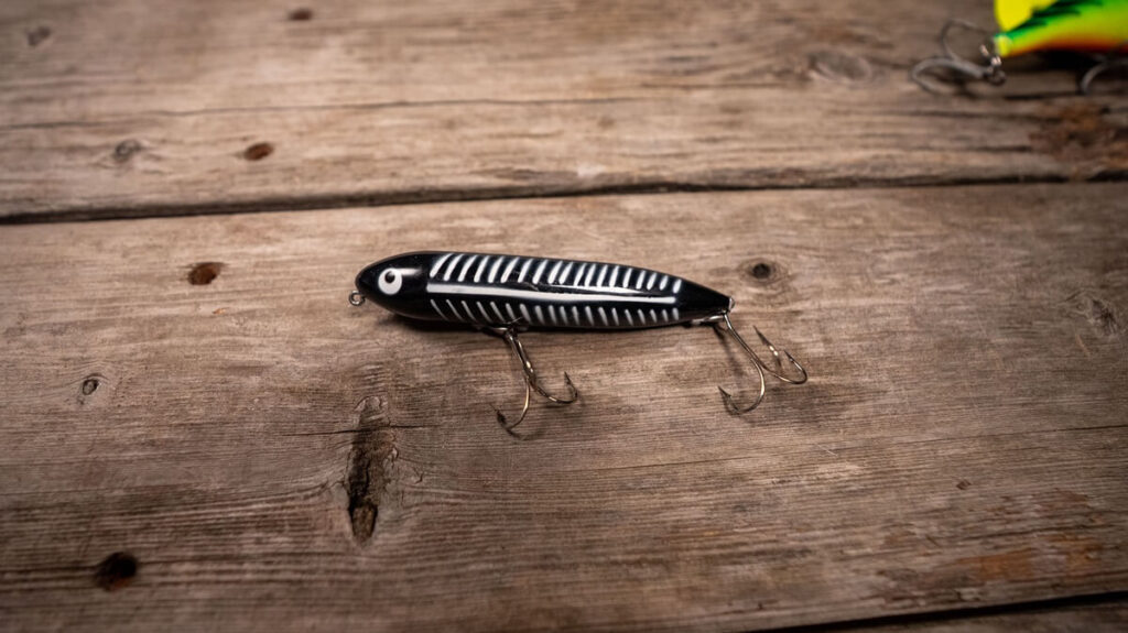 black and white Heddon's Zara Spook lying on a table with other muskie lures