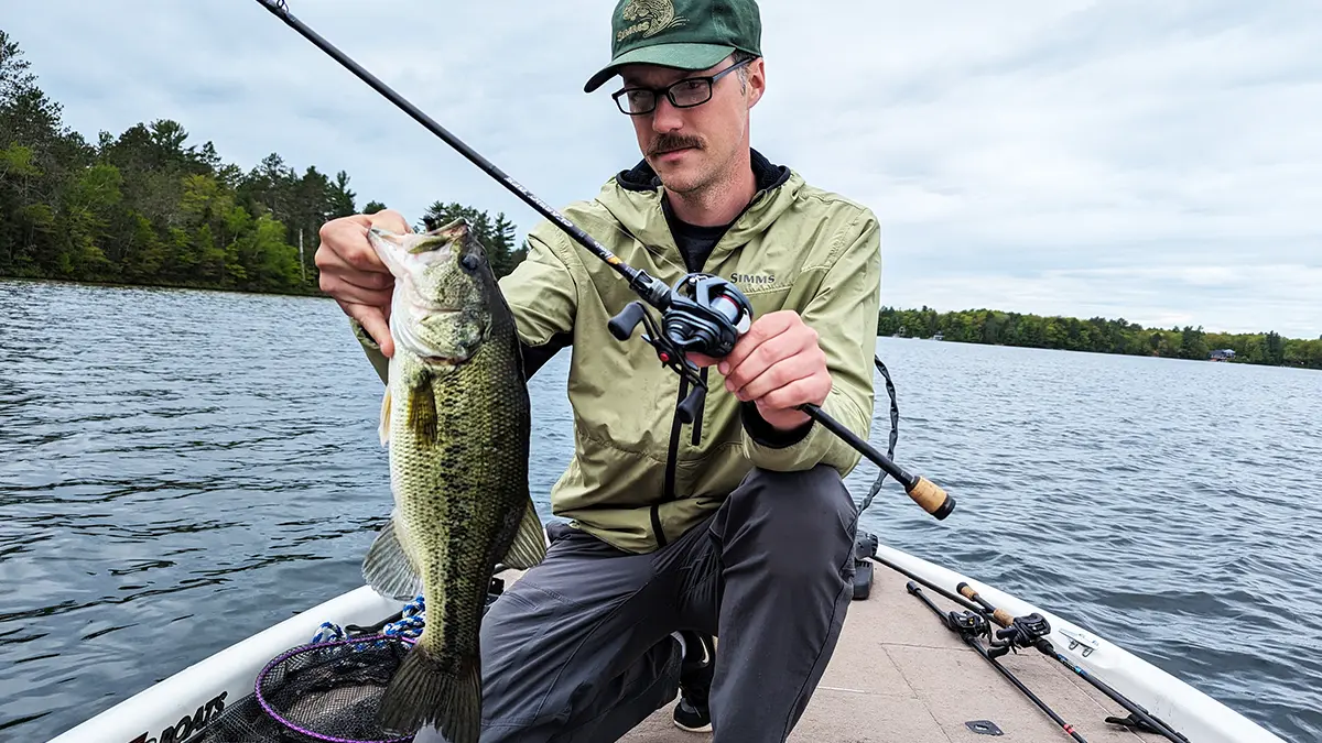 Hobie Wan Kenobi kneeling on a boat with a bass and phenix rod with a Daiwa Tatula BF TW 70 reel