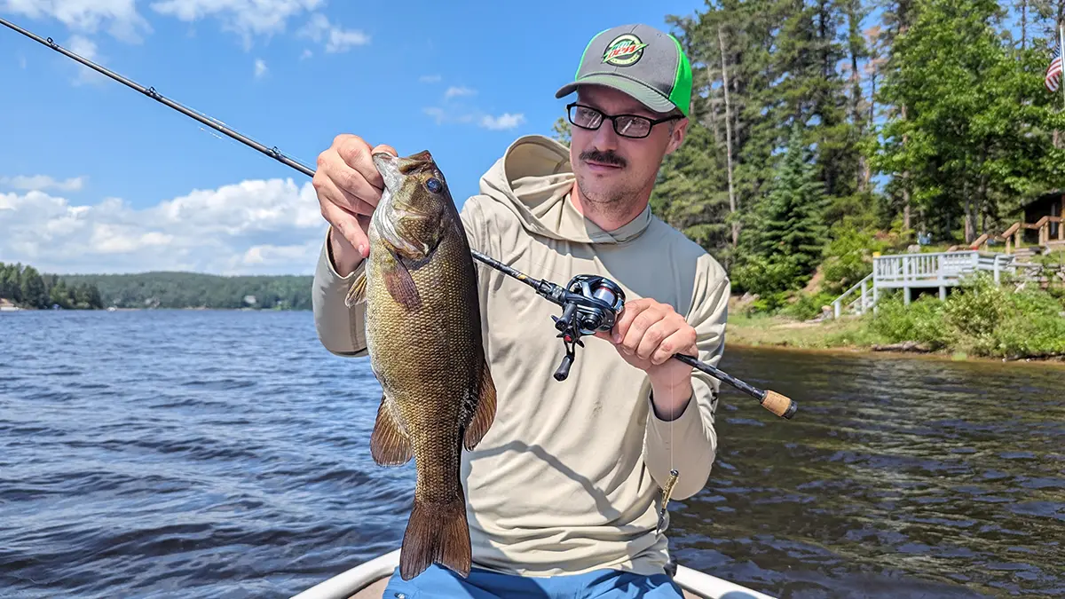 Hobie Wan Kenobi sitting in a boat holding a fish with a rod using the Daiwa Tatula BF TW 70 reel 