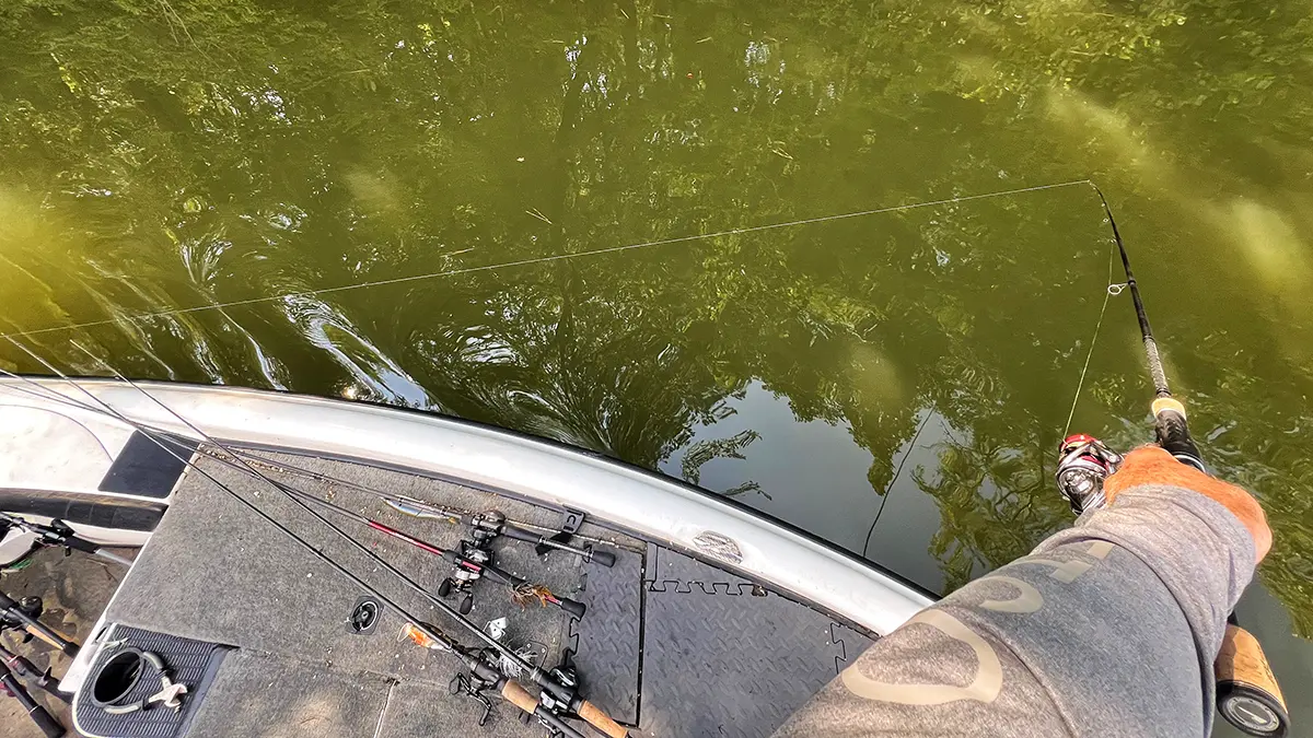 angler dipping rod into water to deal with line twists after cutting bait off