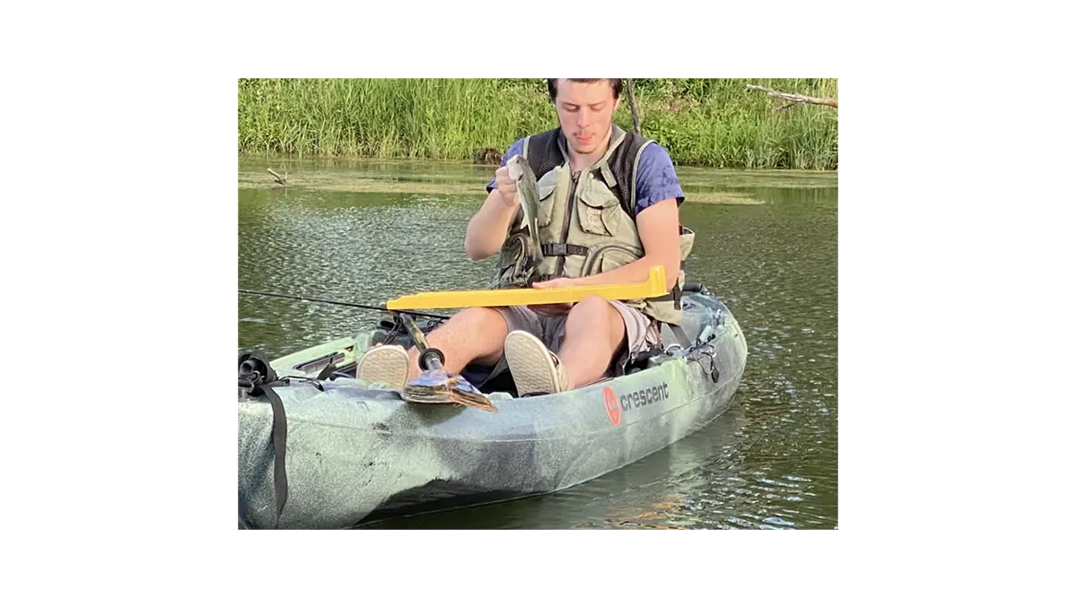 an angler in a kayak measuring a fish with a bump board