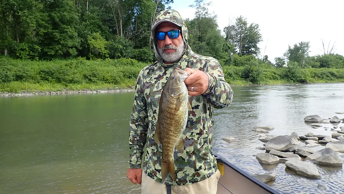 angler with smallmouth in creek