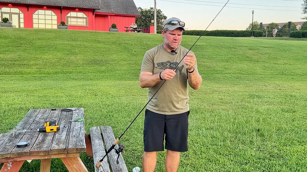 Step 7: rig your rod and bait. Angler Shaye Baker standing by a picnic table rigging his St. Croix Mojo Bass Trigon rod with Seviin GS Series spinning reel