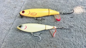 yellow whopper plopper above a yellow white choppo laying on a deck boat