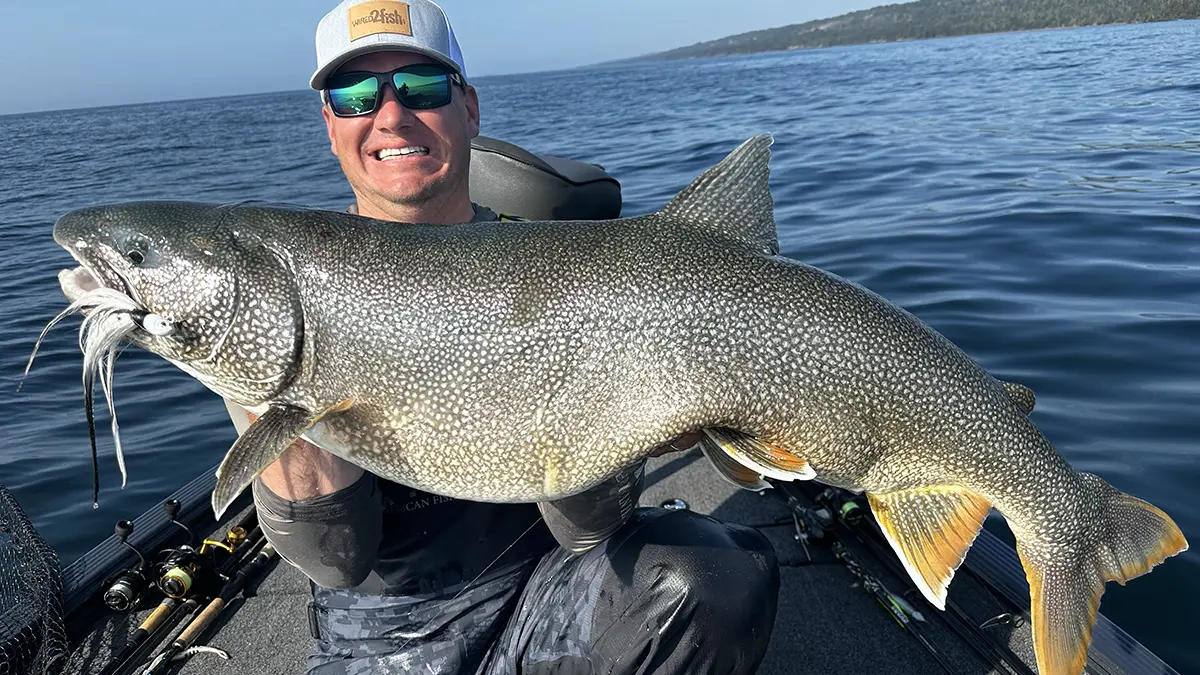 Kyle Peterson holding a large trout on a boat