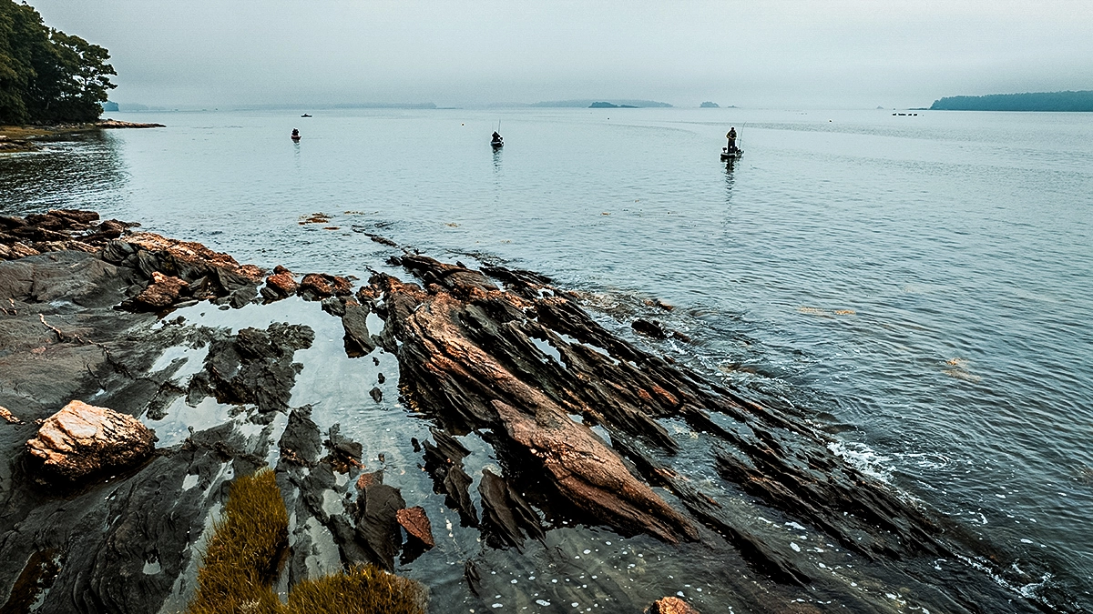 anglers in old town kayaks casting seen from rocky coast