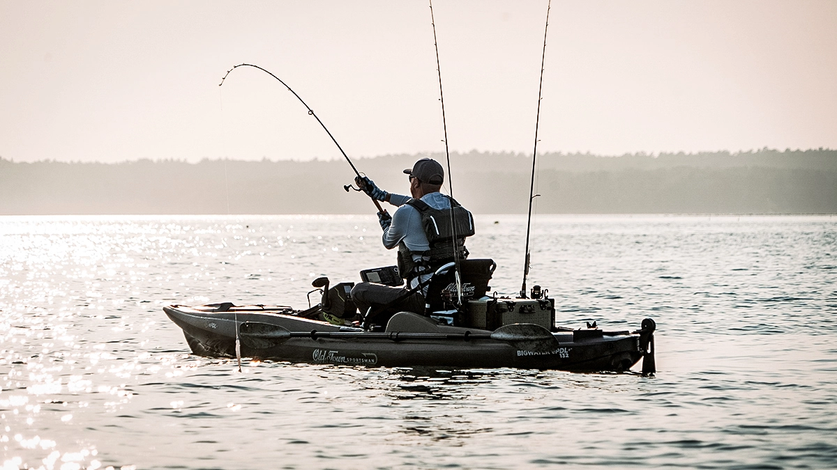 angler in old town sportsman kayak with a fish on the line