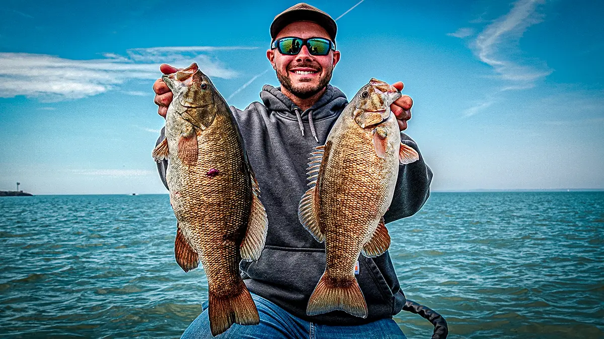 spring bass fishing man holding up two largemouth bass