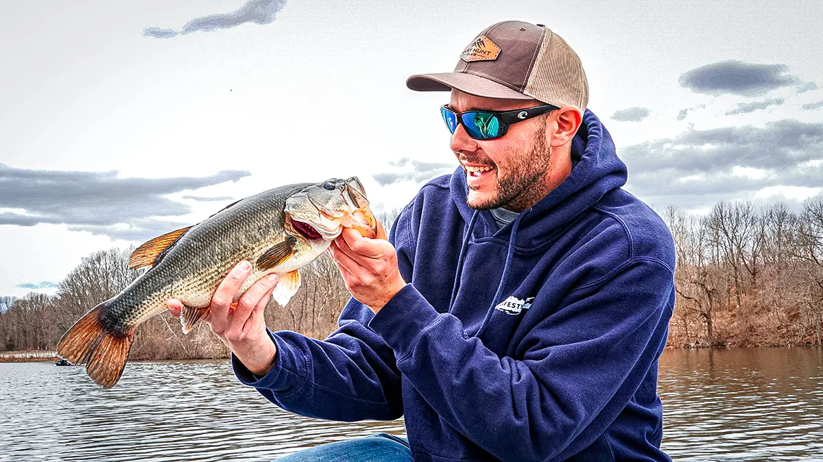 spring bass fishing man holding up a largemouth bass